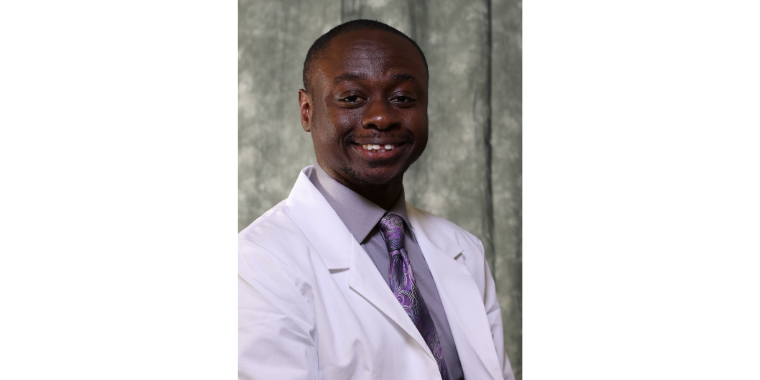 KCU student doctor Reggie Boateng smiles in his white coat. 